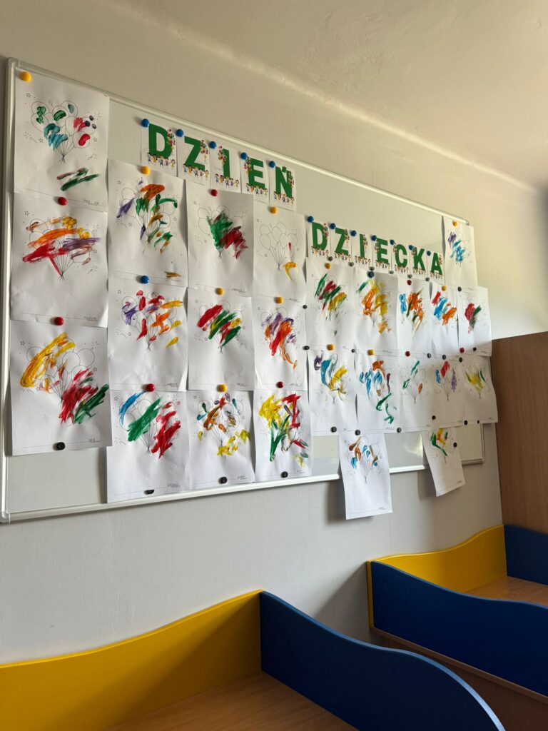 Szatnia drugiej grupy, prace plastyczne grupowiczów, w tle niebiesko-żółte szafki